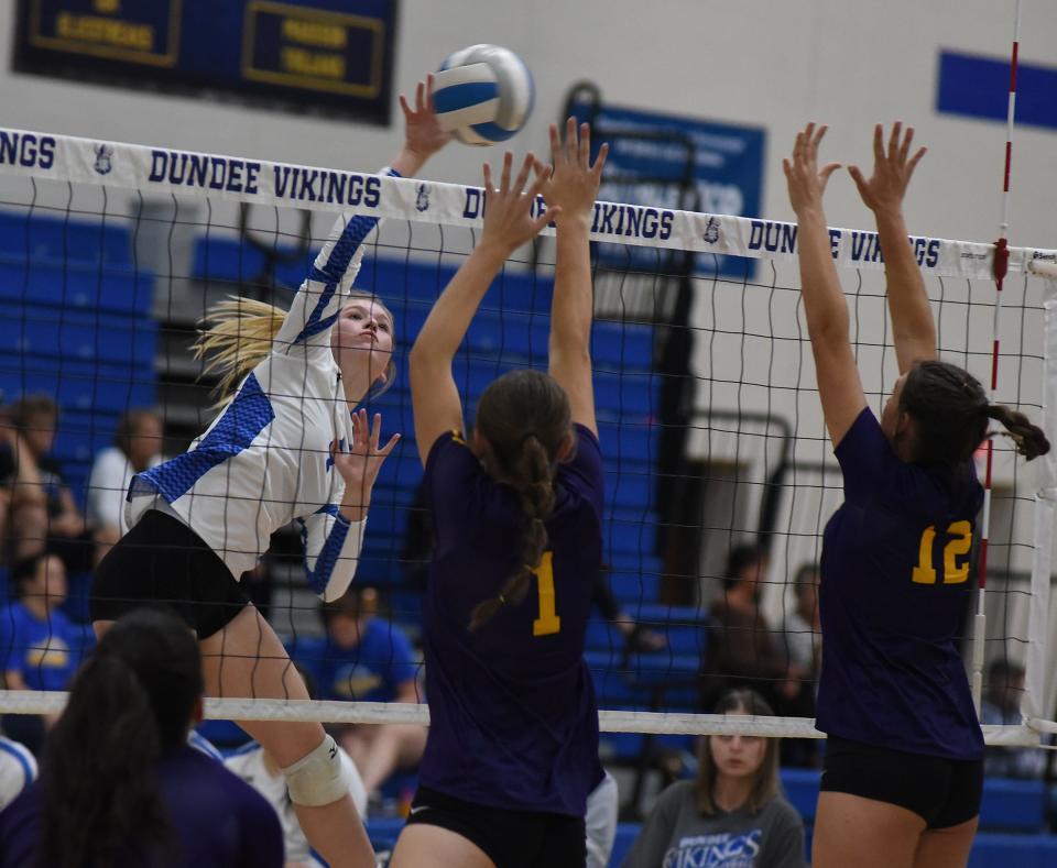 Kennedy Irwin of Dundee spikes past Nicole Brewer and Bella Treloar of Blissfield in Lenawee County Athletic Association round robin play on Tuesday, October 24, 2023 at Dundee.