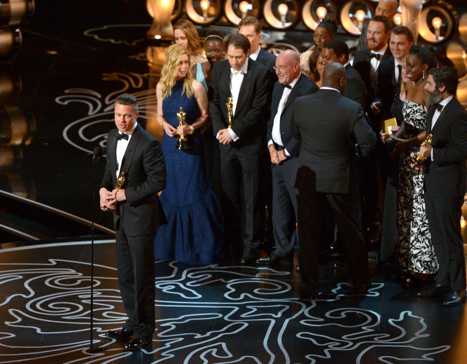 Brad Pitt, left, speaks as he and the cast and crew of "12 Years a Slave" accept the award for the best picture during the Oscars at the Dolby Theatre on Sunday, March 2, 2014, in Los Angeles. (Photo by John Shearer/Invision/AP)