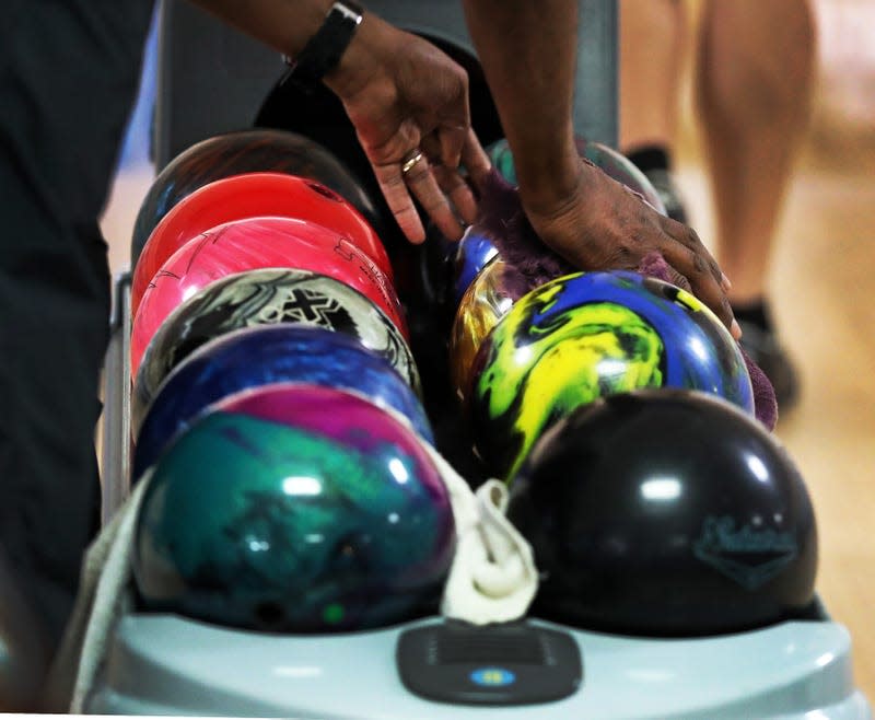 A bowler picks up his ball from the rack that also contains the balls of all the other players in the match at The Westgate Lanes bowling alley in Brockton, MA on Oct. 8, 2020.