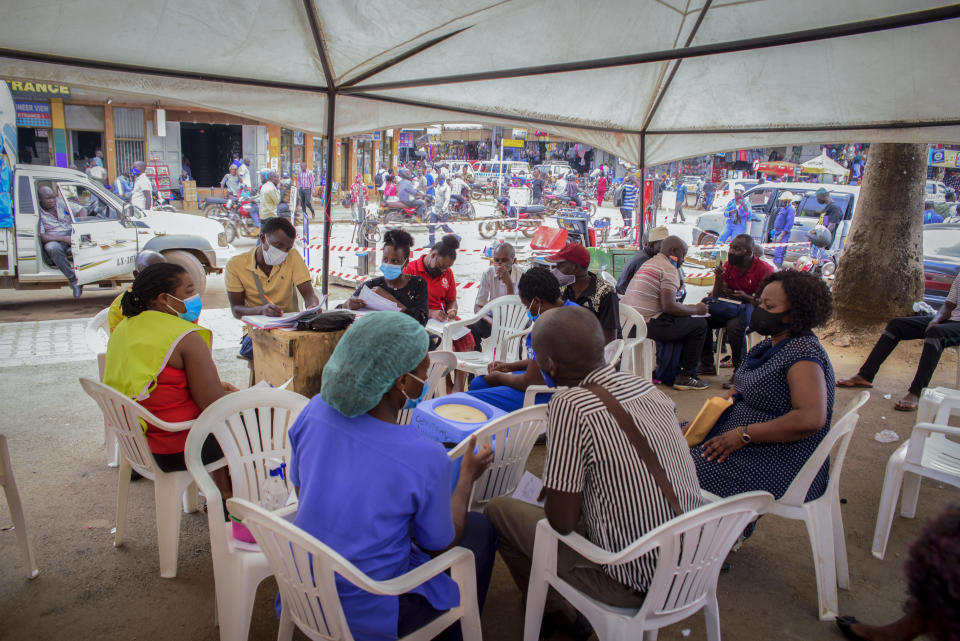 People wait to receive coronavirus vaccinations at a streetside vaccination tent in downtown Kampala, Uganda Tuesday, Sept. 7, 2021. Uganda is accelerating its vaccination drive in order to administer 128,000 doses that recently arrived and expire at the end of September. (AP Photo/Nicholas Bamulanzeki)