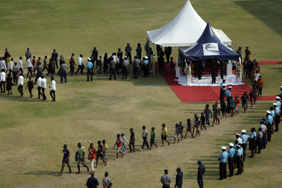 Zimbabweans queue to pay their last respects at a viewing of the remains of former Zimbabwean President Robert Mugabe, under canopy, at the Rufaro Stadium in Harare, Friday, Sept. 13, 2019. A family spokesman says Mugabe will be buried at the national Heroes' Acre site but it is not yet clear when. (AP Photo/Themba Hadebe)