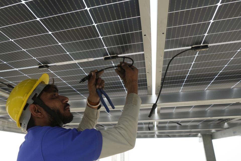 A worker of Solar Square joins a cable after putting up solar panels on the rooftop of a residence in Gurugram on the outskirts of New Delhi, India, Tuesday, Feb. 20, 2024. India is renewing its push to add rooftop solar to meet the needs of a fast-growing nation that's hungry for energy. (AP Photo/Manish Swarup)