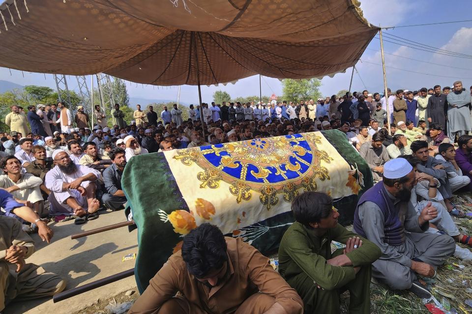 Relatives and residents gather with the body of a school van driver who was killed by a gunman in an attack Monday, as they block a road during a protest demanding the immediate arrest of the attacker, in Mingora, Swat Valley, Pakistan, Tuesday, Oct. 11, 2022. Thousands of people protested in northwest Pakistan on Tuesday after the attack killed the driver and critically injured a child, a decade after schoolgirl Malala Yousufzai was shot by the Taliban in the same city. (AP Photo/Sherin Zada)