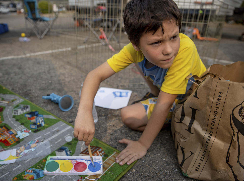 Adrian Childress, 7, paints at the the Green Valley Community Church evacuation shelter on Thursday, Aug. 19, 2021, in Placerville, Calif., after his family fled the Caldor Fire. (AP Photo/Ethan Swope)