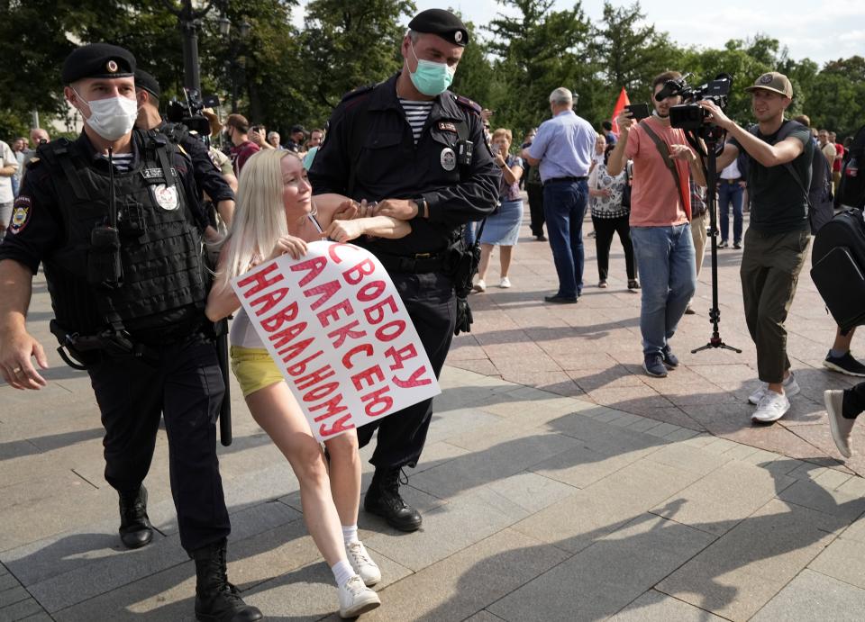 FILE - In this Aug. 14, 2021, file photo, Russian police detain an opposition activist with a poster reading "Freedom to Alexei Navalny" during an anti-vaccination protest in the center of Moscow, Russia. Imprisoned Russian opposition leader Navalny and his embattled allies won't be running in the Sept. 19 parliamentary election, but they still hope to challenge the ruling United Russia party with their strategy known as Smart Voting. (AP Photo/Alexander Zemlianichenko, File)