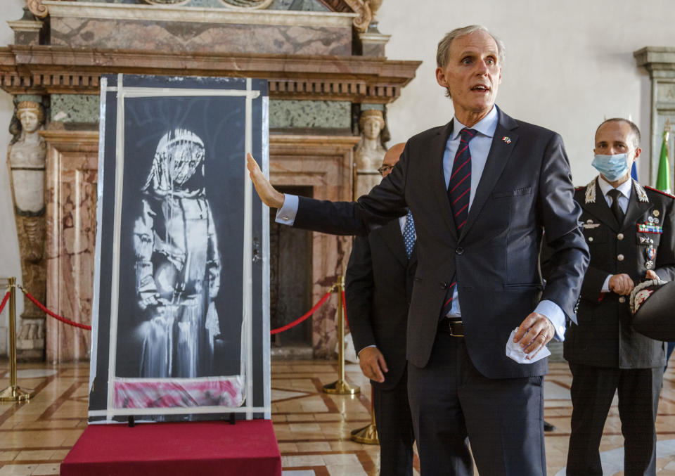 El embajador de Francia en Italia, Christian Masset, recibe de fiscales italianos una obra recuperada del artista británico Banksy, pintada en honor a las víctimas del ataque terrorista del 2015 en la sala de conciertos Bataclan en París, durante una ceremonia en la embajada francesa en Roma el martes 14 de julio de 2020. La obra fue robada en 2018 y recuperada en junio de 2020 en una casa de campo en Italia. (AP Foto/Domenico Stinellis)