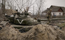 A Ukrainian serviceman walks on an abandoned Russian army tank in Andriivka, Ukraine, Tuesday, April 5, 2022. Ukrainian President Volodymyr Zelenskyy accused Russian troops of gruesome atrocities in Ukraine and told the U.N. Security Council on Tuesday that those responsible should immediately be brought up on war crimes charges in front of a tribunal like the one set up at Nuremberg after World War II. (AP Photo/Vadim Ghirda)
