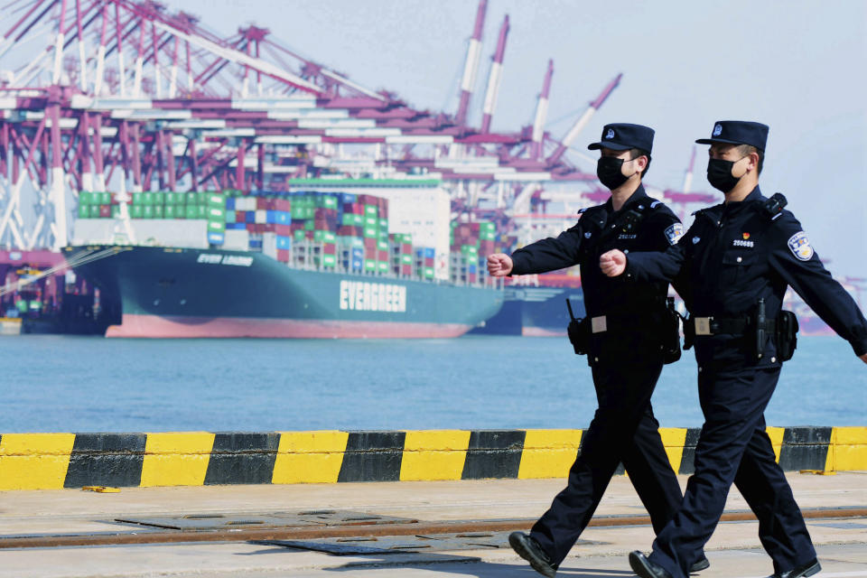 In this Feb. 19, 2020, photo, police officers wearing face masks patrol at a container port in Qingdao in eastern China's Shandong Province. China on Friday, Feb. 21 suspended more punitive tariffs on imports of U.S. industrial goods in response to a truce in its trade war with Washington that threatened global economic growth. (Chinatopix via AP)