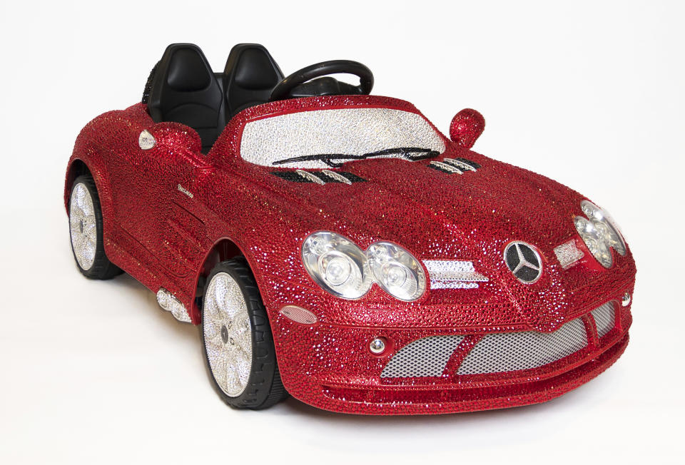 This image released by FAO Schwarz shows a ride-on Mercedes-Benz adorned with more than 44,000 Swarovski crystals in glittery red, white and black for $25,000. (FAO Schwarz via AP)