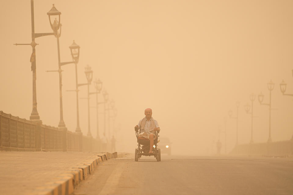 A man navigates his wheelchair on a street during a sand storm in Baghdad, Iraq, Monday, May 23, 2022. (AP Photo/Hadi Mizban)