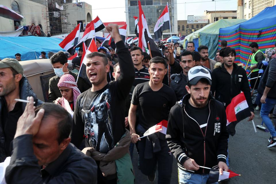 Hundreds of people march inside Tahrir Square carrying national flags and chanting religious slogans in Baghdad, Iraq, Thursday, Dec. 5, 2019. Anti-government protesters at least 15 people have suffered stab wounds in Baghdad's Tahrir Square, the epicenter of their movement, after political parties and Iran-backed militia groups briefly joined them, raising fears of infiltration by authorities. (AP Photo/Hadi Mizban)