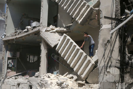 A man gestures as he stands on a damaged building at a site hit by airstrikes in the rebel held area of al-Kalaseh neighborhood of Aleppo, Syria. REUTERS/Abdalrhman Ismail