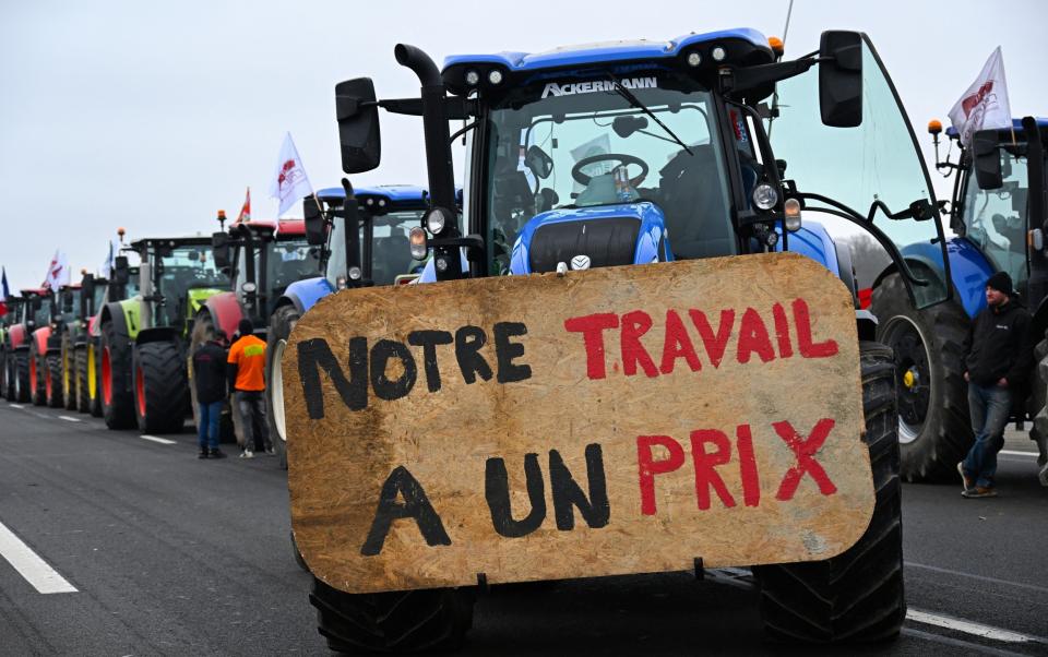 A tractor displays a banner reading "Our work has a price", as farmers coming from Meuse and Moselle blocked the A4 highway near Jossigny, east of Paris