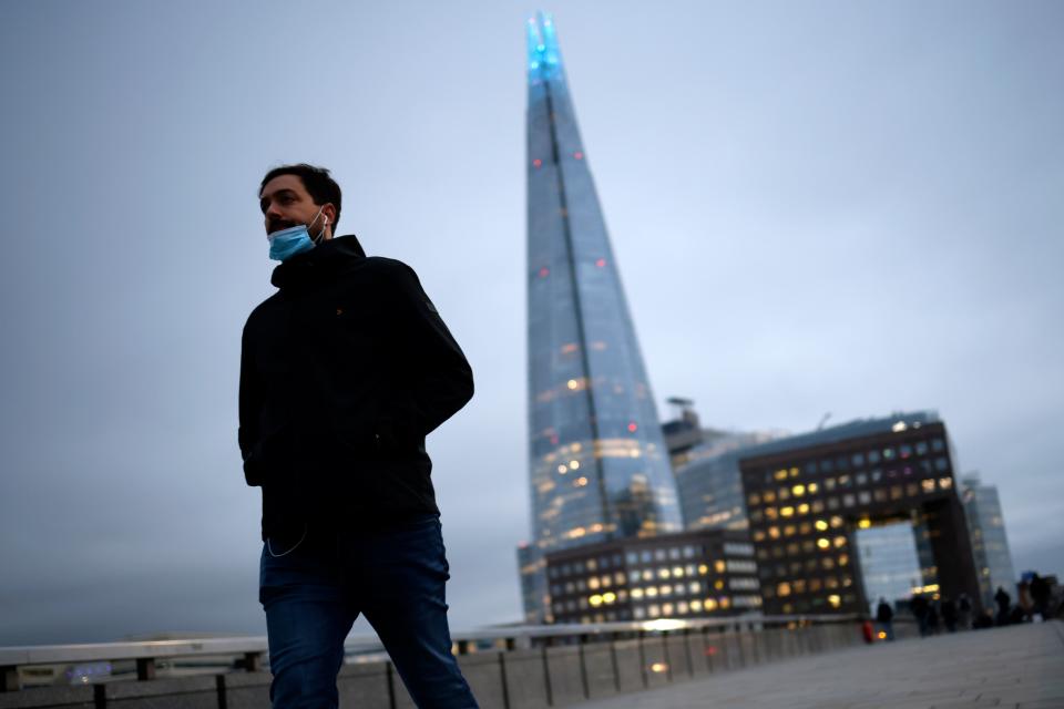 A pedestrian crosses London Bridge with the Shard tower in the background. Photo: Tolga Akmen/AFP via Getty