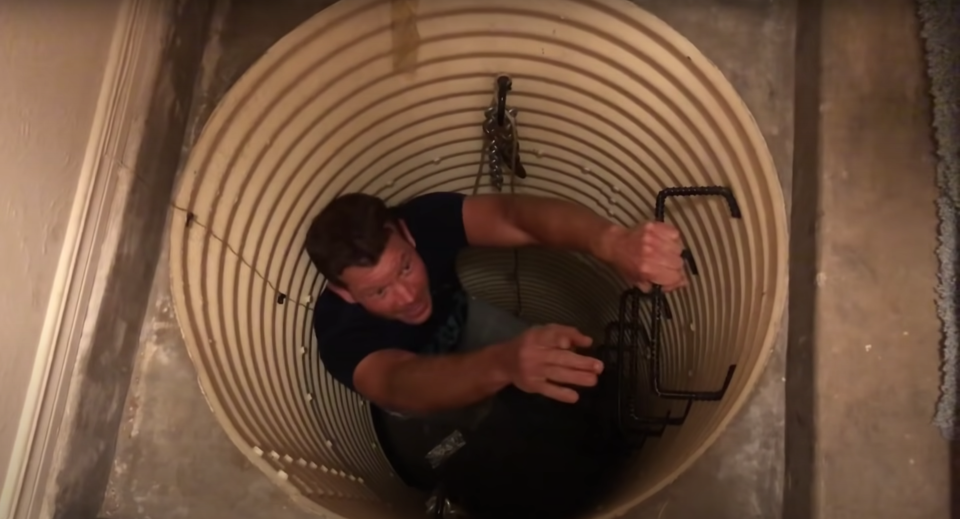 A man descending down an access tunnel into a bomb shelter underneath a house in New Mexico.