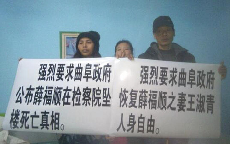 In this Feb. 7, 2014 photo released by Citizen Watchers Group, three members of a spontaneous Citizens Watchers Group hold up two placards, demanding investigations into the death of an activist’s father, in a hotel in Xuzhou, in eastern China's Jiangsu province. Scores of activists from around China have been converging on an eastern town during the Chinese New Year holiday to demand an investigation into the death of a fellow activist’s father at a government building. Words on the placards read: "Strongly demand the city government of Qufu to release the truth of Xue Fushun's death after falling from the city prosecutor's office building, left," and "Strongly demand the city government of Qufu to release Xue Fushun's wife Wang Shuqing from custody." (AP Photo/Citizen Watchers Group) EDITORIAL USE ONLY