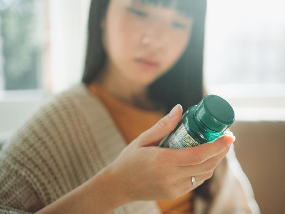 Woman looking at bottle of supplements