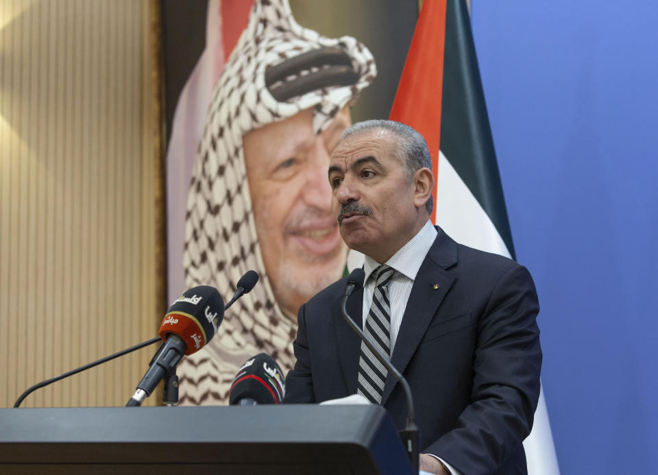 Palestinian Prime Minister Mohammad Ishtayeh chairs the weekly cabinet meeting, at his office in the West Bank city of Ramallah, Monday, Aug. 17, 2020. A portrait of the late Palestinian leader Yasser Arafat hangs in the background. (AP Photo/Nasser Nasser, Pool)