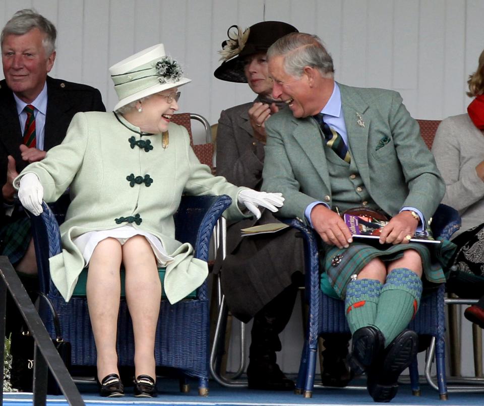 Queen Elizabeth and Prince Charles laugh as they watch a game of tug of war