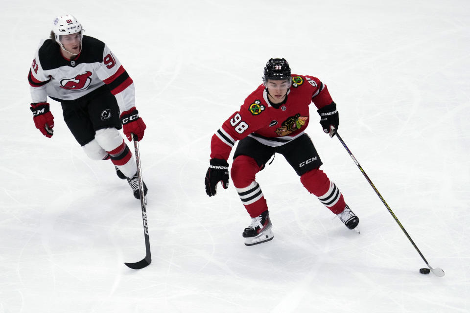 Chicago Blackhawks center Connor Bedard, right, controls the puck against New Jersey Devils center Dawson Mercer, left, during the first period of an NHL hockey game in Chicago, Sunday, Nov. 5, 2023. (AP Photo/Nam Y. Huh)