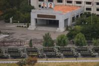 Empty military vehicles line up on a road before a building displaying portraits of late North Korean leaders Kim Il-Sung (top L) and Kim Jong-Il (top R) in Pyongyang on October 10, 2015