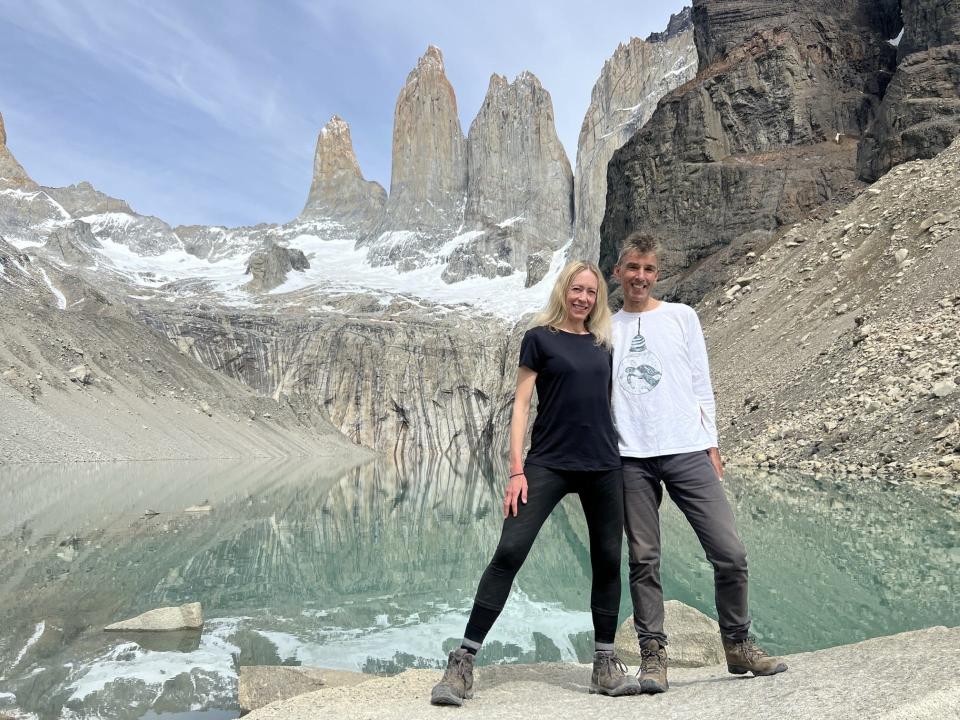 Tina woods hiking in Patagonia with husband, smiling in front of snow-capped mountains