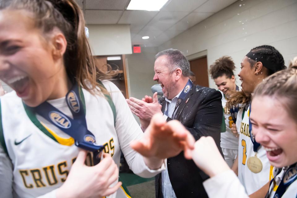 Lansdale Catholic players celebrate in the locker room with head coach Eric Gidney after winning the PIAA Class 4A Girls' Basketball Championship against Blackhawk at the Giant Center on March 25, 2023, in Hershey. The Crusaders won, 53-45.