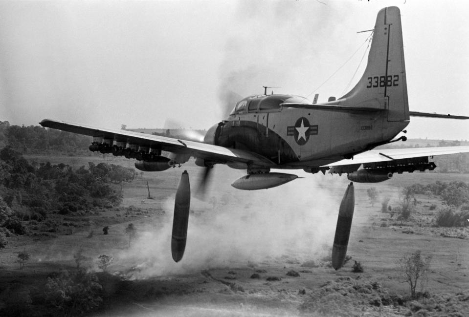 A black and white picture of a A-1 Skyraider dropping bombs on a Viet Cong position in Vietnam.