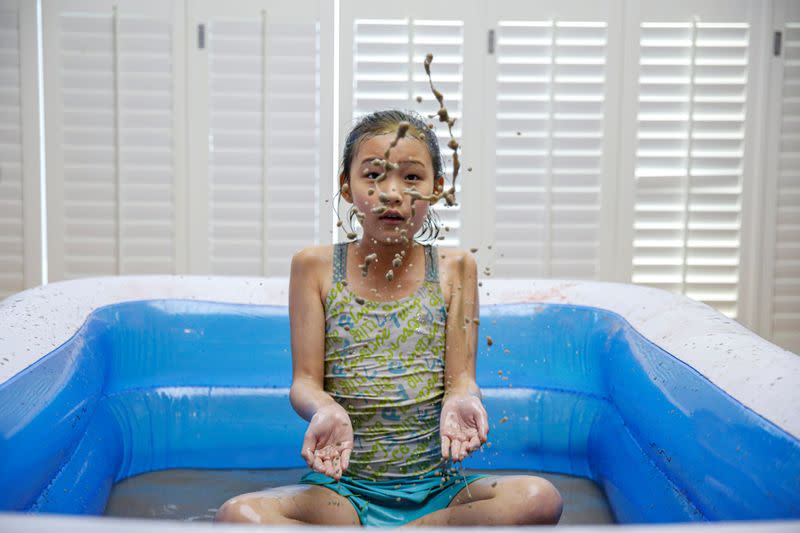A girl plays in a mud pool during the Online Boryeong Mud Festival at her home during a live streaming event, in Gwangju