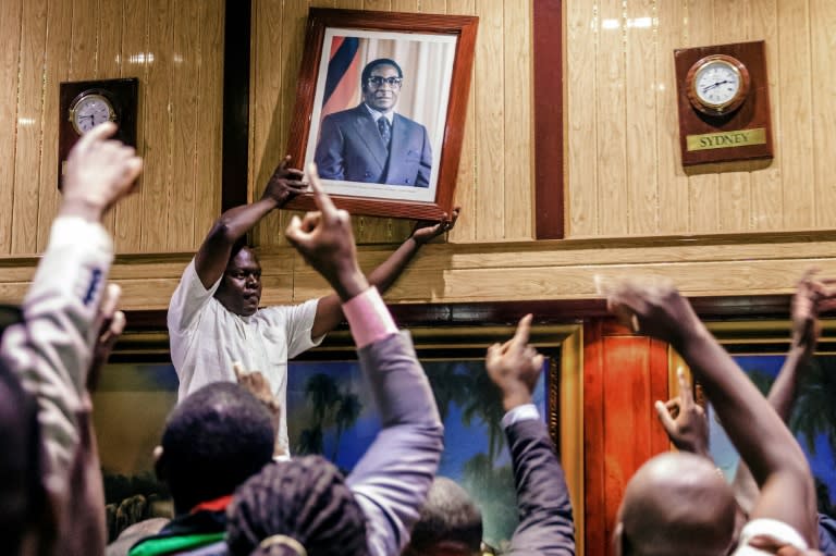 People remove, from the wall at the International Conference centre, where parliament had their sitting, the portrait of former Zimbabwean President Robert Mugabe after his resignation on November 21, 2017 in Harare