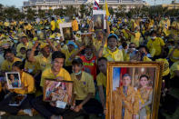 Supporters of Thai monarch display images the royal family ahead of the arrival of King Maha Vajiralongkorn and Queen Suthida to participate in a candle lighting ceremony to mark birth anniversary of late King Bhumibol Adulyadej at Sanam Luang ceremonial ground in Bangkok, Thailand, Saturday, Dec. 5, 2020. (AP Photo/Gemunu Amarasinghe)