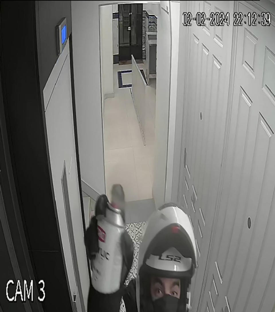This image taken from video provided by U.S. Attorney’s Office, Miami shows a man in a motorcycle helmet spray painting the security camera at Ana Knezevich’s Madrid apartment, on Feb. 2, 2024. David Knezevich, a Florida businessman is accused in the February disappearance of his estranged wife in Spain. Knezevich, 36, pleaded not guilty on Monday, June 10, during a brief hearing at Miami's federal courthouse. (U.S. Attorney’s Office, Miami via AP)
