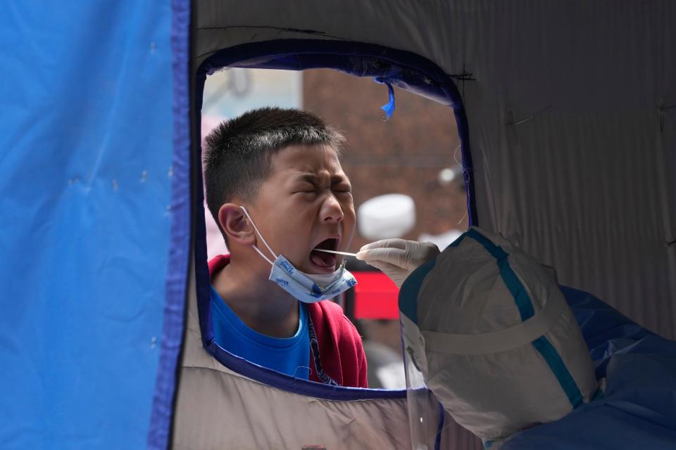 A child opens his mouth to be swabbed for mass COVID test on Thursday, May 12, 2022, in Beijing. China's leaders are struggling to reverse an economic slump without giving up anti-virus tactics that shut down Shanghai and other cities, adding to challenges for President Xi Jinping as he tries to extend his time in power.