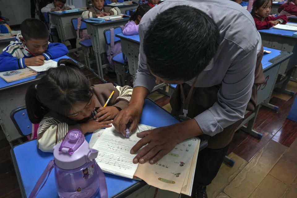 A teacher shows a student how to write Tibetan words on a first-grade class at the Shangri-La Key Boarding School during a media-organized tour in Dabpa county, Kardze Prefecture, Sichuan province, China on Sept. 5, 2023. (AP Photo/Andy Wong)