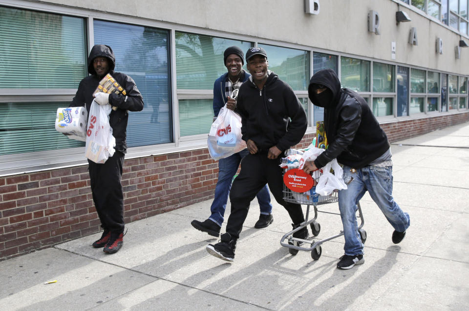 Men carry items, Monday, April 27, 2015, during unrest following the funeral of Freddie Gray in Baltimore. Gray died from spinal injuries about a week after he was arrested and transported in a Baltimore Police Department van. (AP Photo/Patrick Semansky)