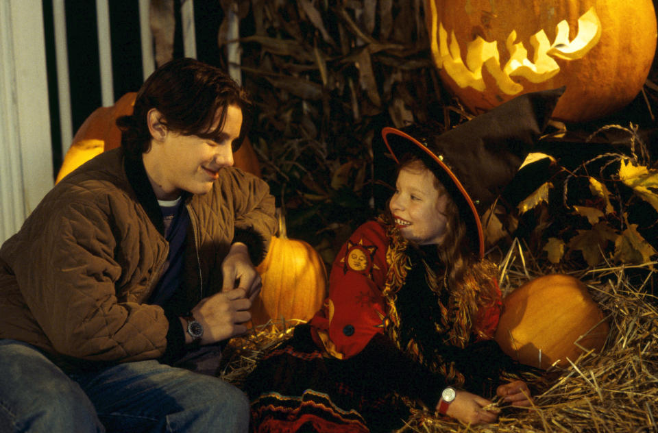 Omri looking at Thora Birch in a scene from Hocus Pocus in which they are sitting in hay surrounded by pumpkins