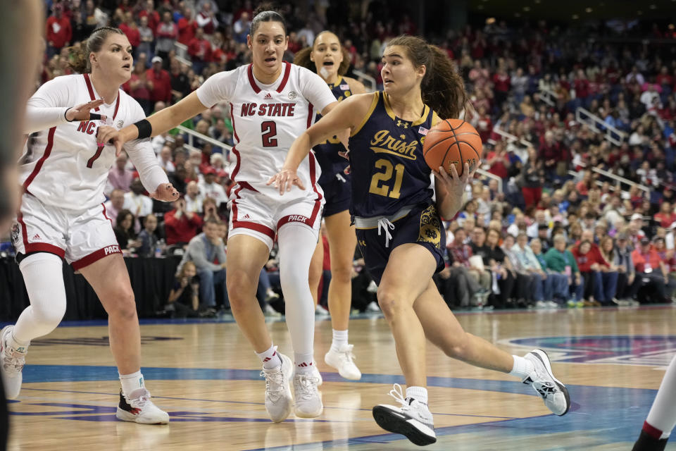 Notre Dame's Maddy Westbeld (21) drives past NC State's Mimi Collins (2) and River Baldwin (1) during the second half of an NCAA basketball game for the Women's Atlantic Coast Conference championship in Greensboro, N.C., Sunday, March 10, 2024. (AP Photo/Chuck Burton)