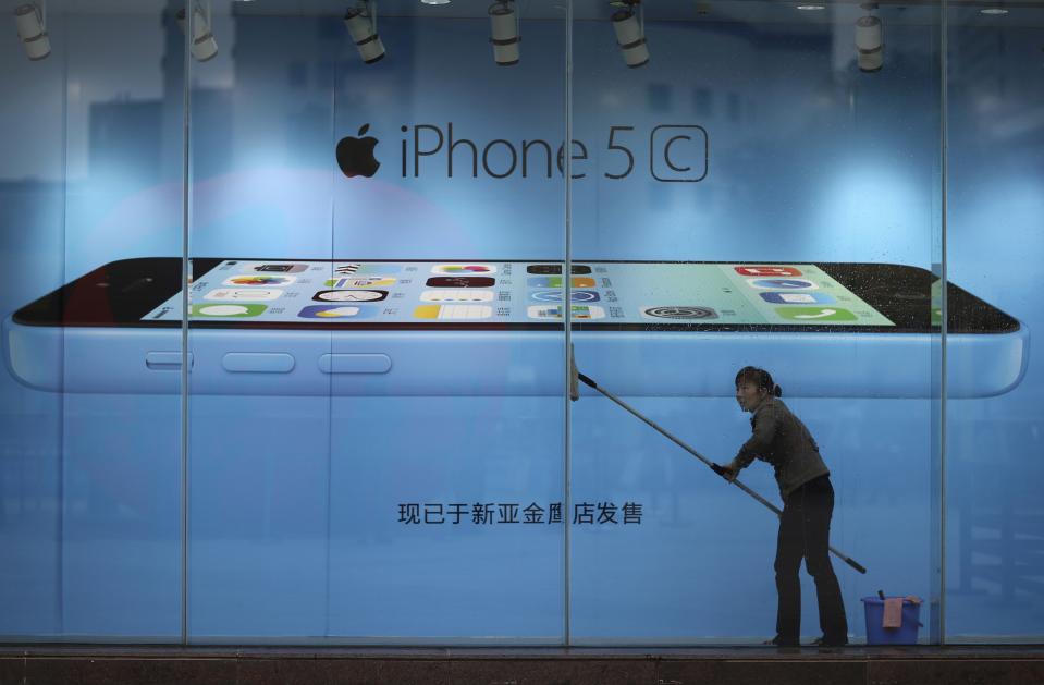 File picture shows a worker cleaning in front of an iPhone 5C advertisement at an apple store in Kunming