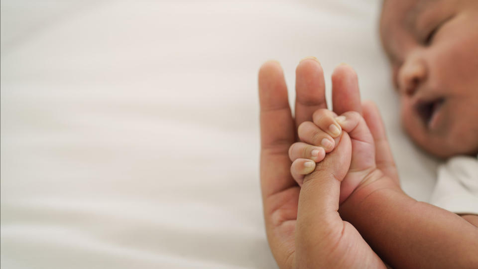 A parent holding a newborn's hand.