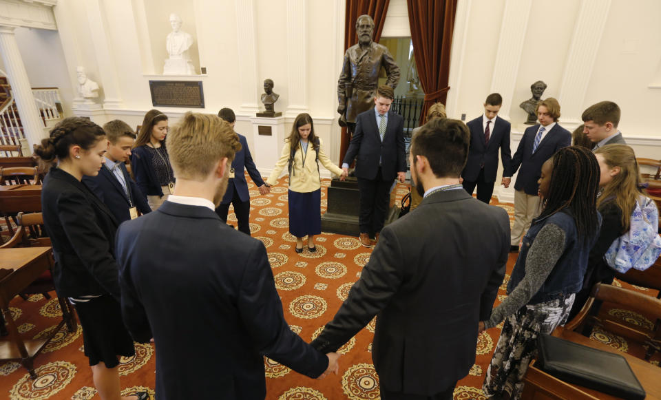 In this Feb. 5, 2019, photo, a group of students from the Teenpact Leadership school pray in front of the statue of Confederate General Robert E. Lee in the old House chambers at the Capitol in Richmond, Va. Virginia has come a long way from its days as a bastion of slavery and white supremacy. But when a racist photo was discovered last week on Gov. Ralph Northam’s 1984 medical school yearbook page, it exposed how much deeply embedded racism still lurks in the state. (AP Photo/Steve Helber)