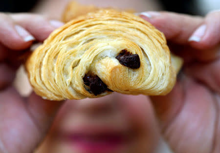 A baker holds a pain au chocolat, also called chocolatine in the Gascony region, in her bakery in Bordeaux, France, May 24, 2018. REUTERS/Regis Duvignau