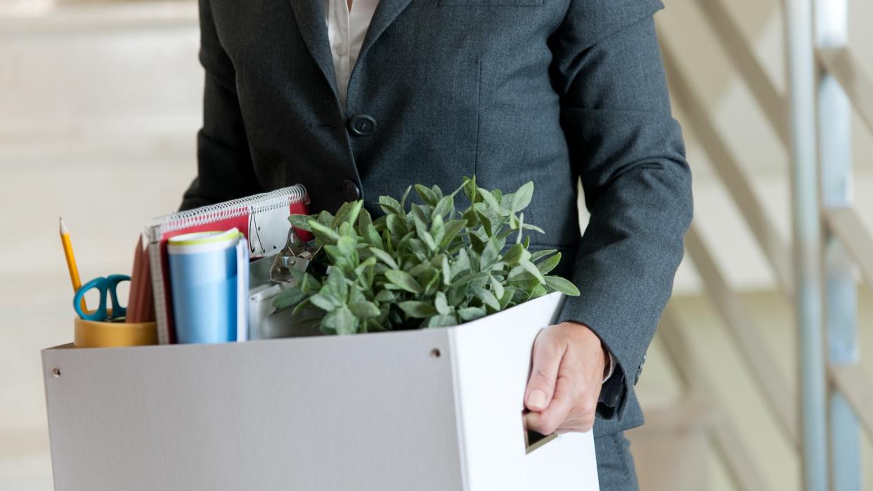 Mid Section View of a Businesswoman Holding a Cardboard Box Containing a Large Group of Objects.