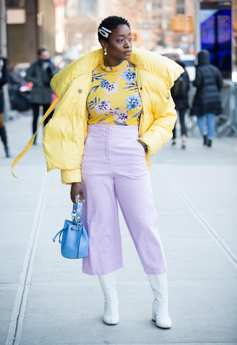 <p>A guest poses outside of the Son Jung Wang show wearing a yellow coat, yellow floral print shirt, light purple pants, white shoes and holding a blue bag. <em>[Photo: Getty]</em> </p>