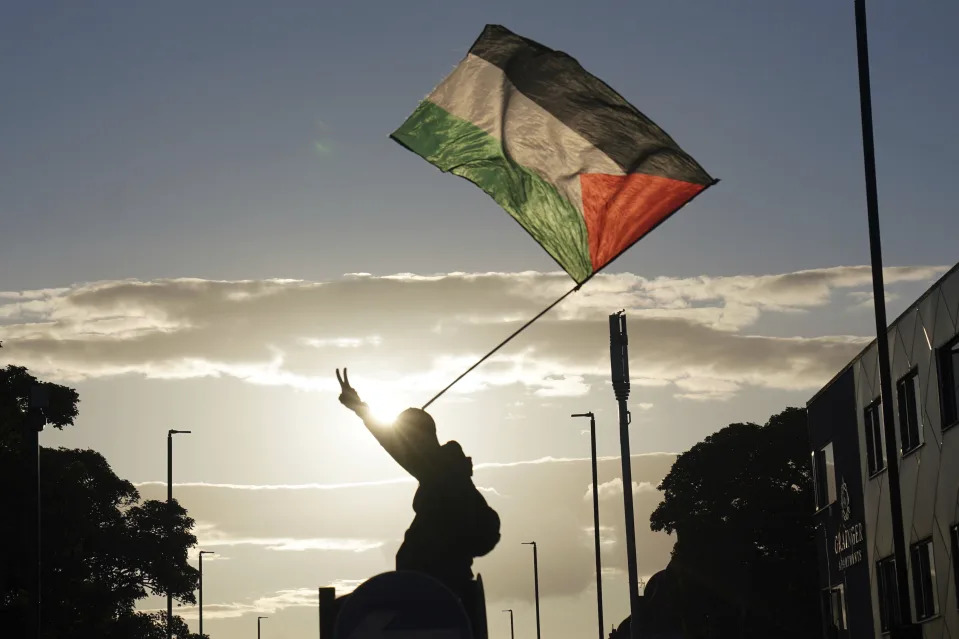 An anti-racism protesters waves a Palestinian flag in Newcastle, England, Wednesday Aug. 7, 2024, as anti-immigration groups plan to demonstrate at dozens of locations throughout the country following a week of rioting fueled by misinformation over a stabbing attack against young girls. (PA via AP)