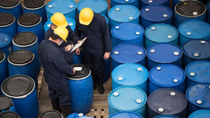 Group of men working at a chemical warehouse classifying barrels.