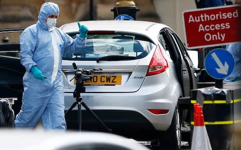 A police officer in a forensics suit next to the car used in the attack - Credit: HENRY NICHOLLS /Reuters