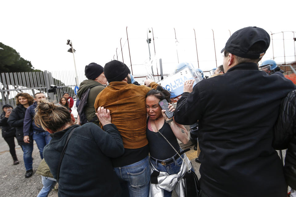 Relatives of Rebibbia prison's inmates face police after inmates staged a protest against new coronavirus containment measures, in Rome, Monday, March 9, 2020. Italian penitentiary police say six inmates protesting coronavirus containment measures at the northern Italian prison of Modena have died after they broke into the infirmary and overdosed on methadone. The protest Sunday in Modena was among the first of more than two-dozen riots at Italy's overcrowded lock-ups that grew Monday. (Cecilia Fabiano/LaPresse via AP)