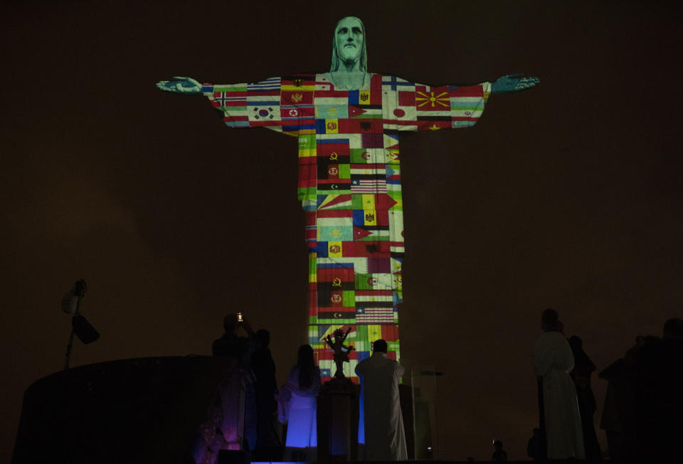 Rio's Christ the Redeemer statue is lit up with the flags of countries currently afflicted by the new coronavirus in Rio de Janeiro, Brazil, Wednesday, March 18, 2020. For most people COVID-19 causes mild or moderate symptoms. For others, especially the elderly and people with existing health problems, it can cause many other serious illnesses, including pneumonia. (AP Photo/Silvia Izquierdo)