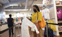 FILE - In this Tuesday, June 30, 2020, file photo, a woman shops for clothing in a Gap store during the coronavirus pandemic, in New York. Unemployment remains painfully high in the U.S. even as economic activity is slowly picking up. That reality will be on display Thursday, July 16, 2020, when the U.S. government releases data on the number of laid off workers seeking unemployment benefits the week prior and retail sales in June. (AP Photo/Mark Lennihan, File)