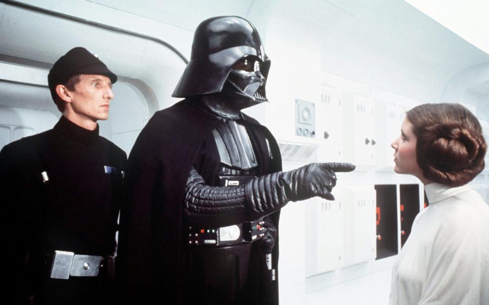 David Prowse as Darth Vader in Star Wars: Episode IV - A New Hope (1977), with Al Lampert and Carrie Fisher who revealed that the cast had nicknamed Prowse 'Darth Farmer' -  CAP/KFS